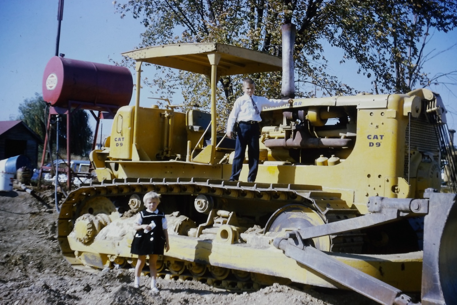 The kids climb a CAT D9 bulldozer on the construction site, 1963